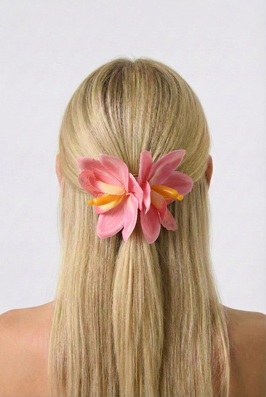 Person with long blonde hair wearing a pink flower hair clip on a white background
