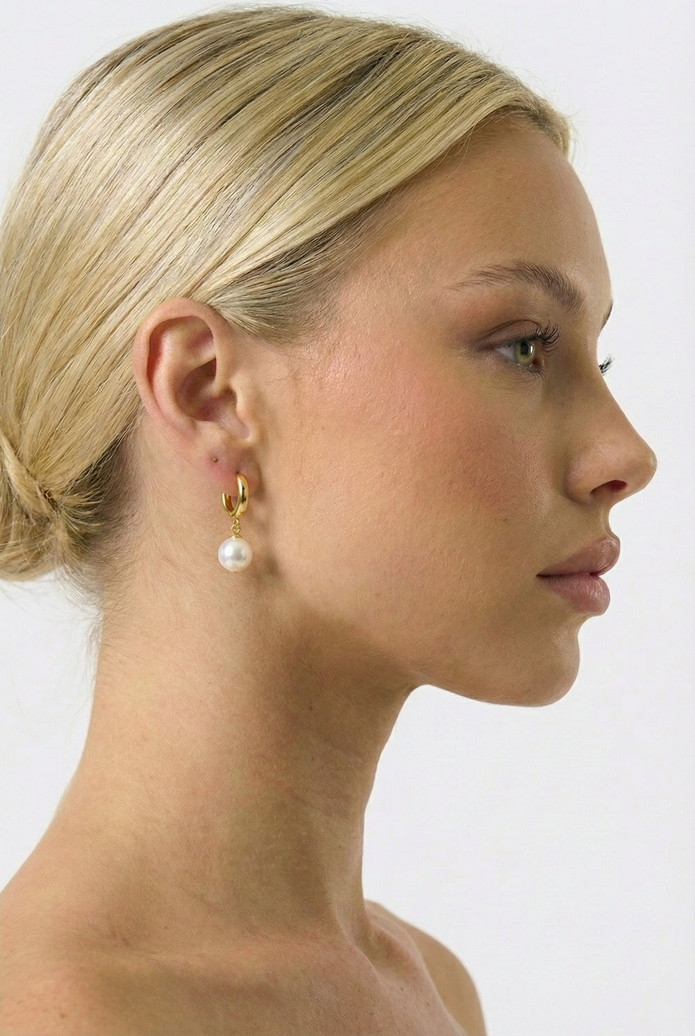 Woman wearing gold earrings with a white background