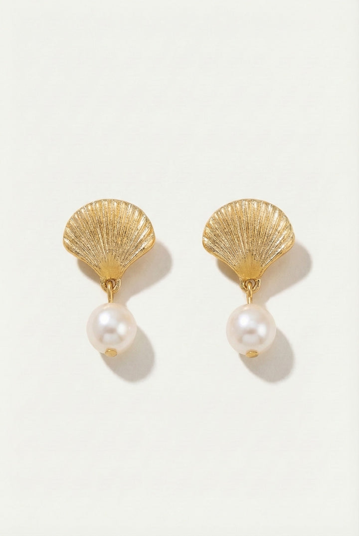 Gold shell earrings with pearl drops on a white background